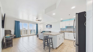 Een moderne keuken met een groot eiland, een zithoek met een bank en een balkon met gordijnen.