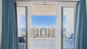 Een balkon met uitzicht op een strand en hotelgebouwen.