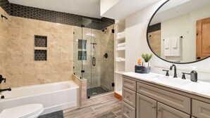 Een moderne badkamer met bad, toilet, douche en wastafel.
