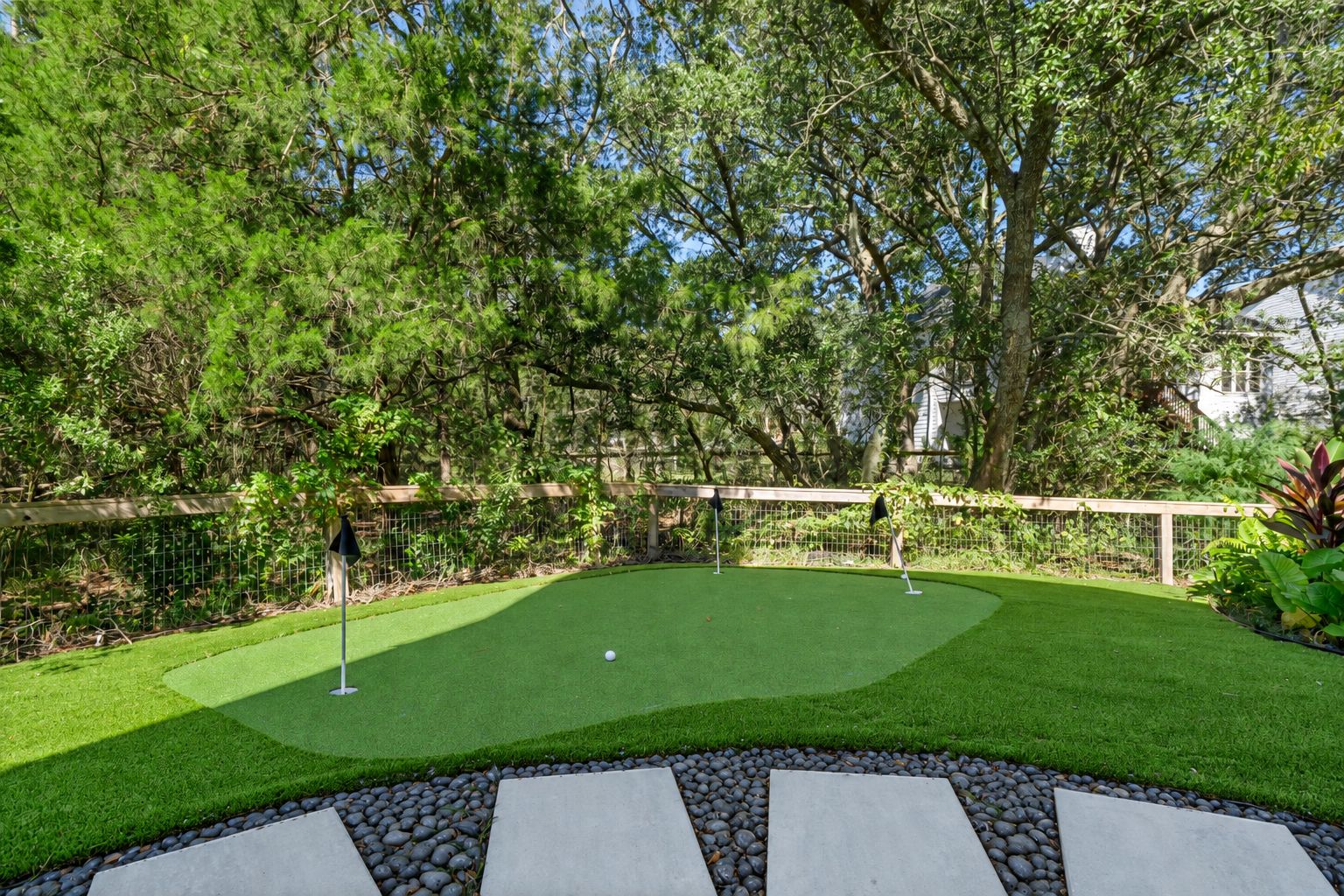 A well-maintained artificial grass golf course with a stone pathway leading to the tee area.