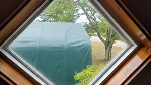 A skylight with a view of a tree and a grassy area. - Sleeps 10, close to shopping centers on quiet dead end street. (Brunswick)