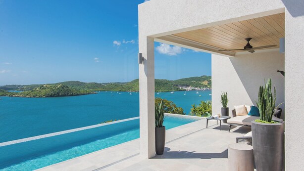 Un área de estar exterior moderna con piscina y vistas al mar.