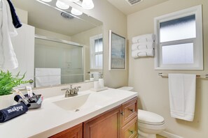 Ein modernes Badezimmer mit einem weißen Waschbecken, einem Holz-Waschtisch und einer weißen Toilette. Über dem Waschbecken hängt ein großer Spiegel, und es gibt ein Fenster mit Milchglas.