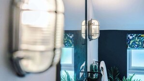 Casa de banho com espelho, porta-toalhas e janela com vista para plantas.