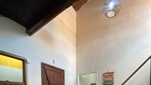 A dining area with a wooden table set for two, a wooden door, and a staircase with a handrail.