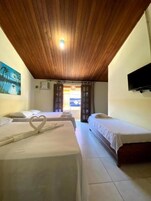 Quarto de hotel com duas camas, teto de madeira, televisão fixada na parede e um quadro na parede.