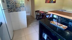 A kitchen with a tiled backsplash, a dining area with chairs, and a painting on the wall.