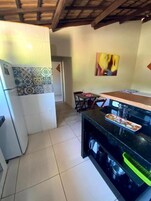 Uma cozinha com painel de azulejos, uma área de refeições com cadeiras e um quadro na parede.
