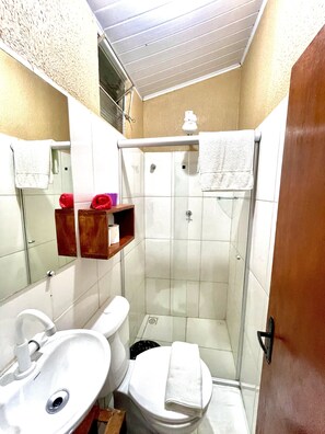 A bathroom with a sink, toilet, and shower. There are towels hanging on the wall and a mirror above the sink.