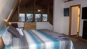 Une chambre à coucher avec un lit, une commode et une fenêtre donnant sur un beau paysage.