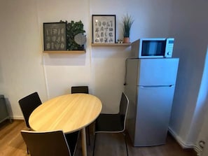 Una cucina compatta con tavolo e sedie, un frigorifero e elementi decorativi alle pareti.