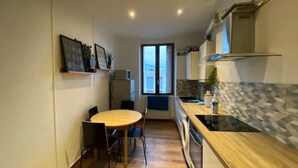 Cocina compacta con una mesa redonda y sillas, horno empotrado y ventana que proporciona luz natural.