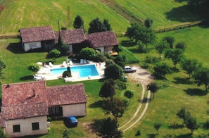 Ein Wohnanwesen mit Pool, mehreren Häusern und einer umliegenden Grünlandschaft.