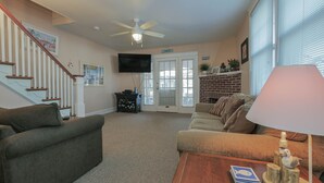 A living room with a staircase, a fireplace, and a television. - Easy beach access!  3 bedroom, 2.5 Bath, a must see! (Ocean City)
