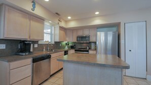 A modern kitchen with light wood cabinets, stainless steel appliances, and a central island. - Easy beach access!  3 bedroom, 2.5 Bath, a must see! (Ocean City)