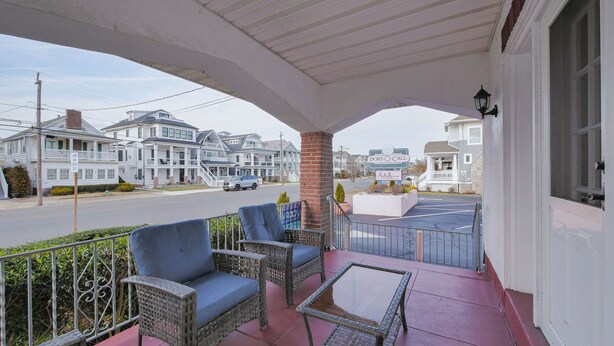 A hotel porch with wicker furniture and a clear view of the street and neighboring houses. - Easy beach access!  3 bedroom, 2.5 Bath, a must see! (Ocean City)