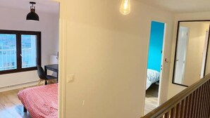 Ein Schlafzimmer mit Bett, Stuhl, Schreibtisch und Fenster.