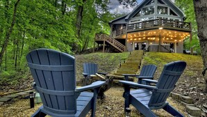 A cabin with a deck and outdoor seating area. - Lideca’s Treehouse | Hot Tub + Fire Pit + Games (Mineral Bluff)