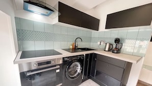 A compact kitchen with a dishwasher, oven, and washing machine, a sink, and a coffee maker. - 017 CHIC & COSY F2 53m2 HYPERCENTRE WIFI SMART TV NETFLIX (Saint-Étienne)