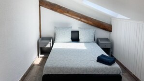A bedroom with a sloped ceiling, a bed with a patterned bedspread, two bedside tables, and a skylight. - 017 CHIC & COSY F2 53m2 HYPERCENTRE WIFI SMART TV NETFLIX (Saint-Étienne)