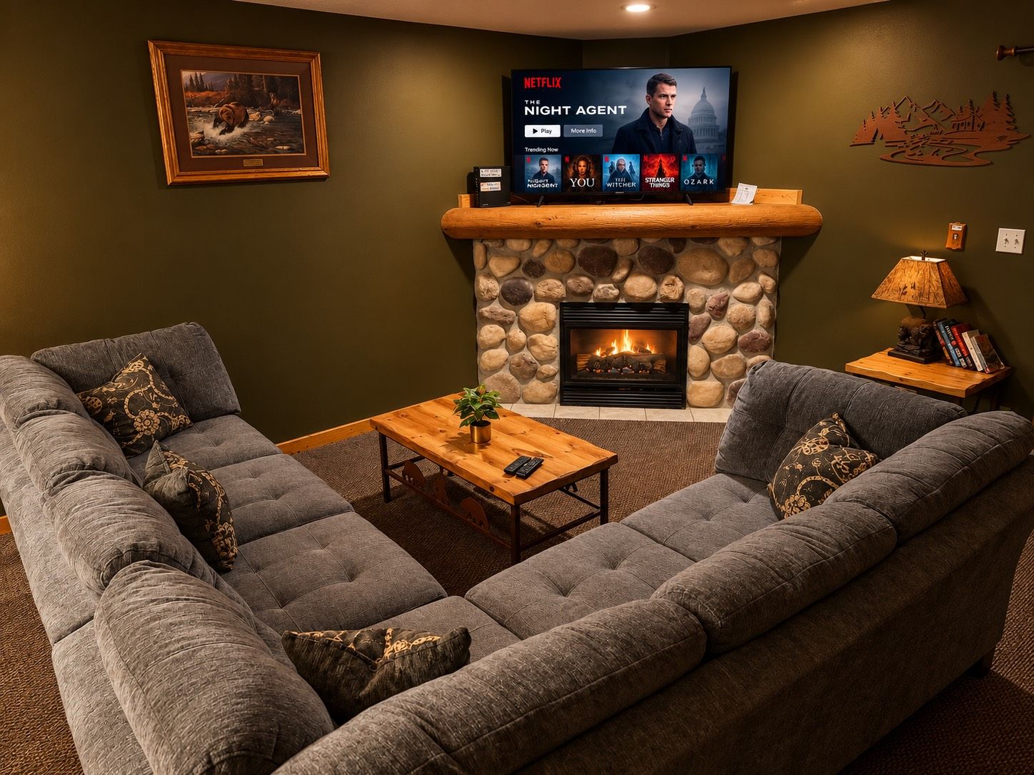 Un salon chaleureux avec une cheminée en pierre, un téléviseur à écran plat diffusant une série Netflix et des fauteuils confortables.