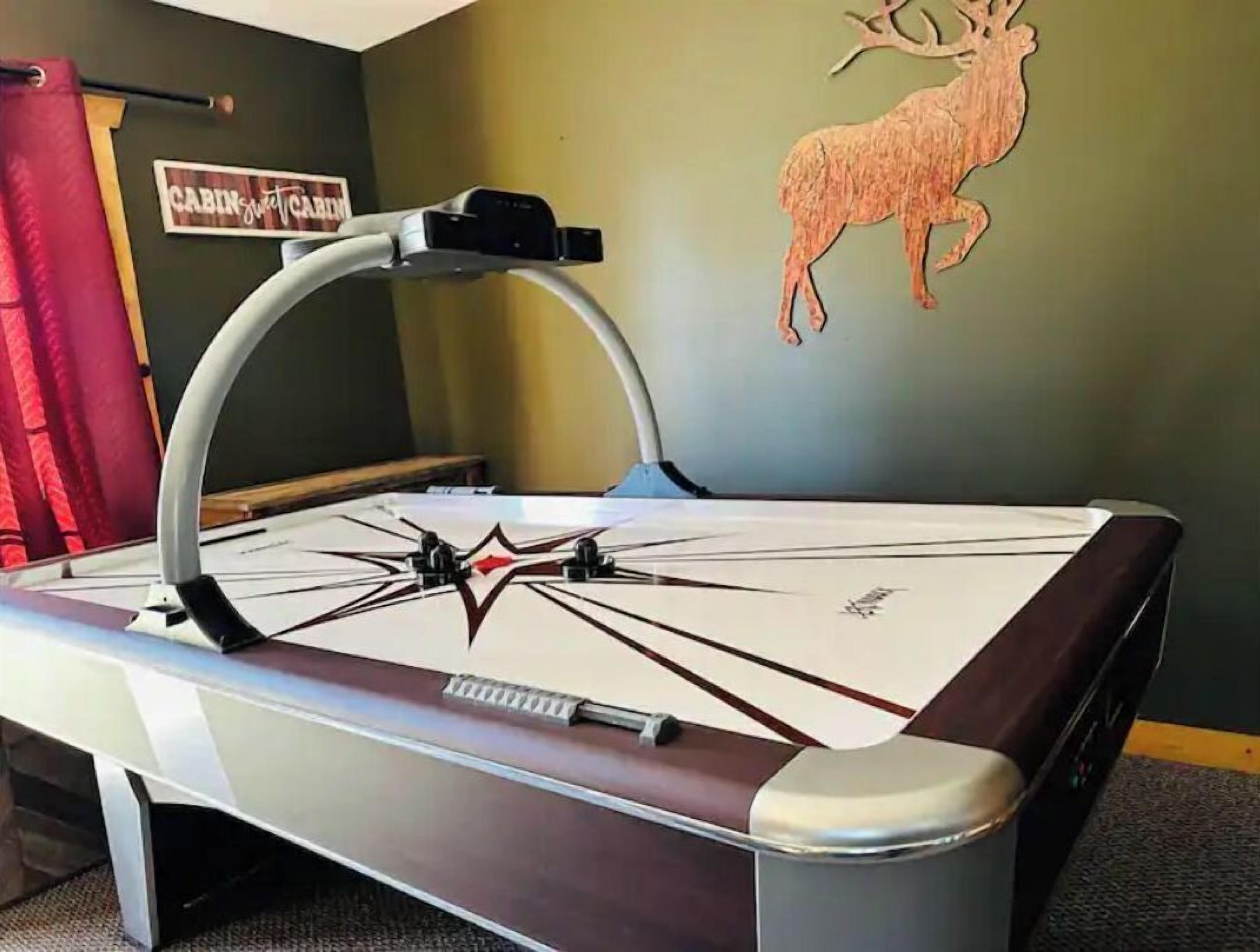 Una mesa de billar con un diseño de estrella en el centro, un soporte de tacos fijado a la pared y una decoración de venado también montada en la pared.