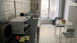 Cozinha compacta com micro-ondas, torradeira e pequena mesa com cadeiras.