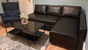 Uma sala de estar com sofá, poltrona, mesa de centro de vidro e tapete estampado.