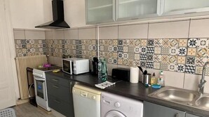 Cozinha compacta com máquina de lavar, micro-ondas e torradeira.