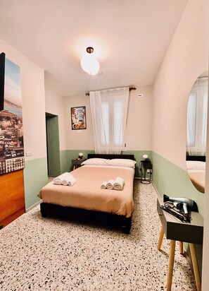 Une chambre d’hôtel avec un lit, une table de chevet, un miroir et un tableau au mur.