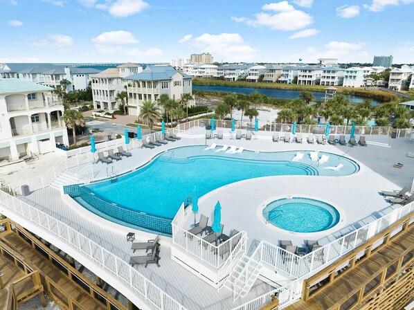 A large outdoor swimming pool with multiple deck levels, surrounded by white railings and lounge chairs.