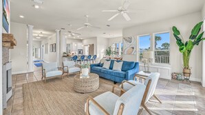 A spacious living room with a blue sofa, light blue armchairs, and a round coffee table. - Private Pool & Spa Walk to 2 Beaches (Destin)