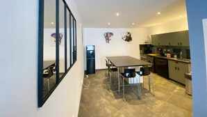 A modern kitchen with a dining area, featuring a large window, a refrigerator, and a sink.
