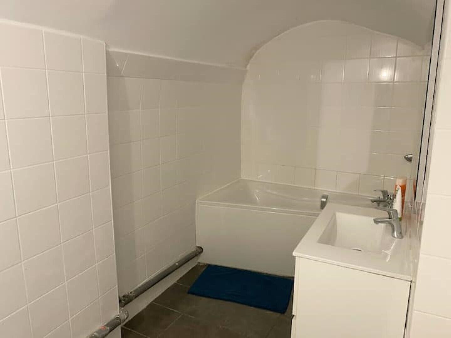 Un bagno piccolo e bianco con una vasca, un lavabo e uno specchio.