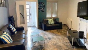 A living room with a sofa, a coffee table, a TV, and a clock on the wall.