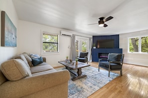 A living room with a sofa, a coffee table, a chair, and a fireplace.