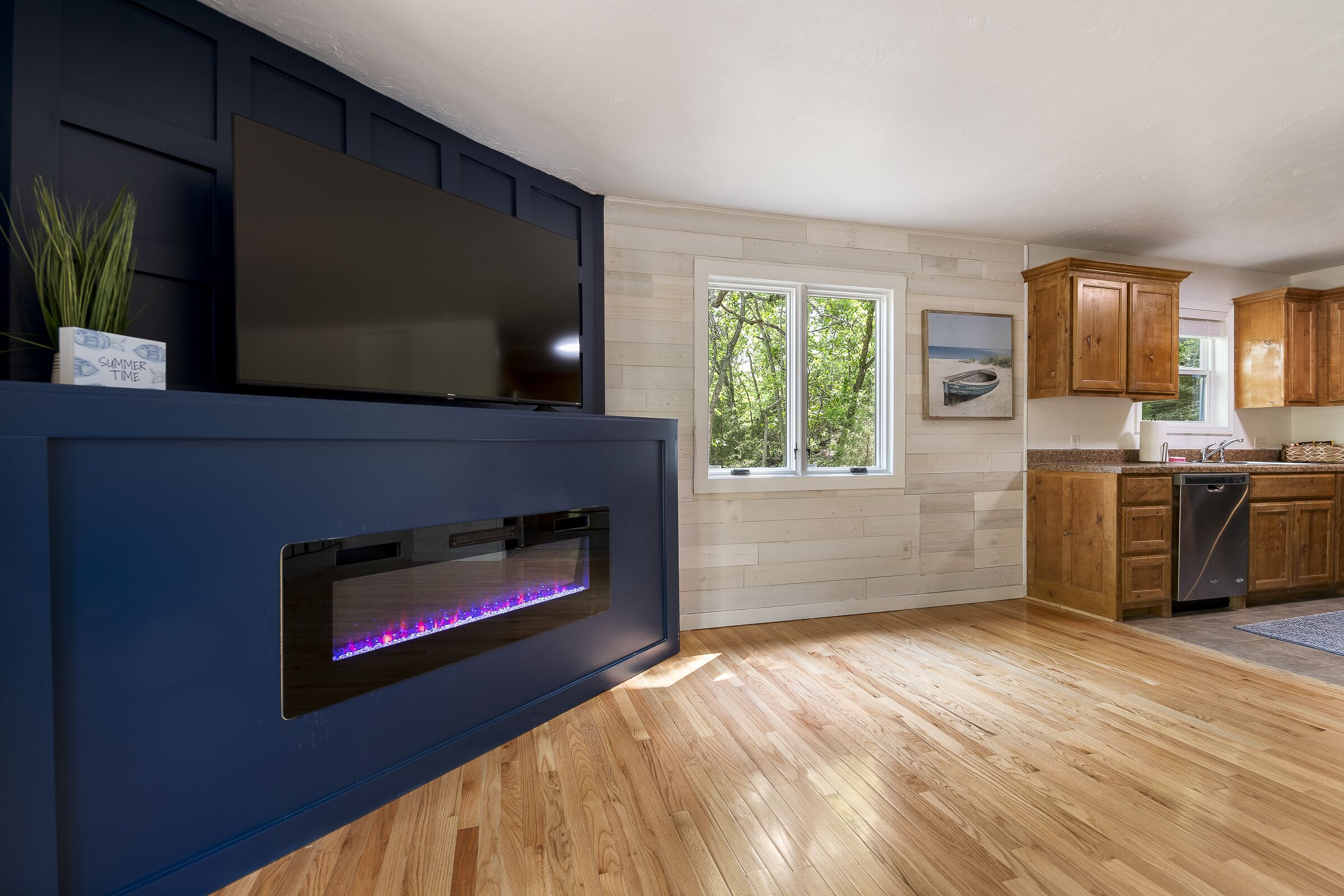 Une cuisine moderne avec des meubles en bois, un four encastré et une grande fenêtre.