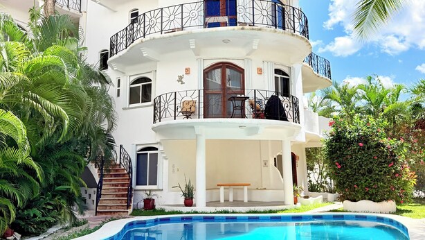 A multi-story building with balconies, a swimming pool, and palm trees. - Perfect Cozumel escape, pool, private beach on quiet north shore (San Miguel de Cozumel)