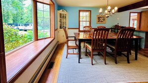 A dining room with a large window, wooden table, and chairs.