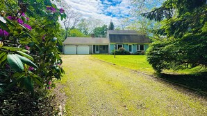 A two-story house with a front lawn, a garage, and a small garden area.