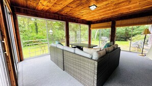 A covered outdoor seating area with wicker furniture and a view of the garden.