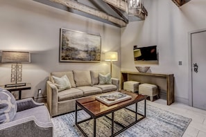 A living room with a sofa, coffee table, and a painting on the wall.