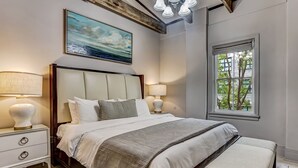 Una camera da letto con un letto grande, due comodini con lampade, una finestra con tende e un quadro appeso al muro.