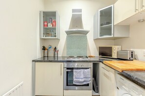 Une cuisine équipée d’une cuisinière, d’un four, d’un four à micro-ondes et d’un placard contenant des ustensiles de cuisine.
