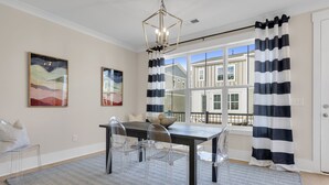 A dining area with a dark wooden table, clear chairs, and a patterned rug. - Downtown Greenville · 3BR/3.5BA · Private 2-Car Garage · Minutes to Main St (Greenville)