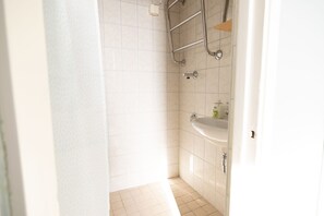 A bathroom with white tiles, a shower, a sink, and a towel rack. - 2ndhomes Central 1BR Top Floor Home (Helsinki)