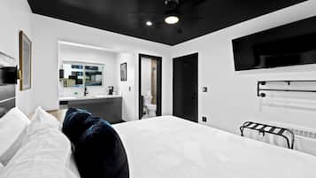 Une chambre d’hôtel moderne dotée d’un grand lit, d’un ventilateur de plafond, d’un téléviseur fixé au mur et offrant une vue sur l’extérieur.