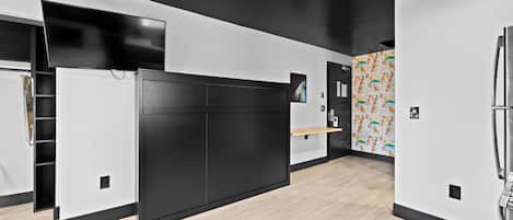 A modern kitchen with a black cabinet, a wooden countertop, and a refrigerator.