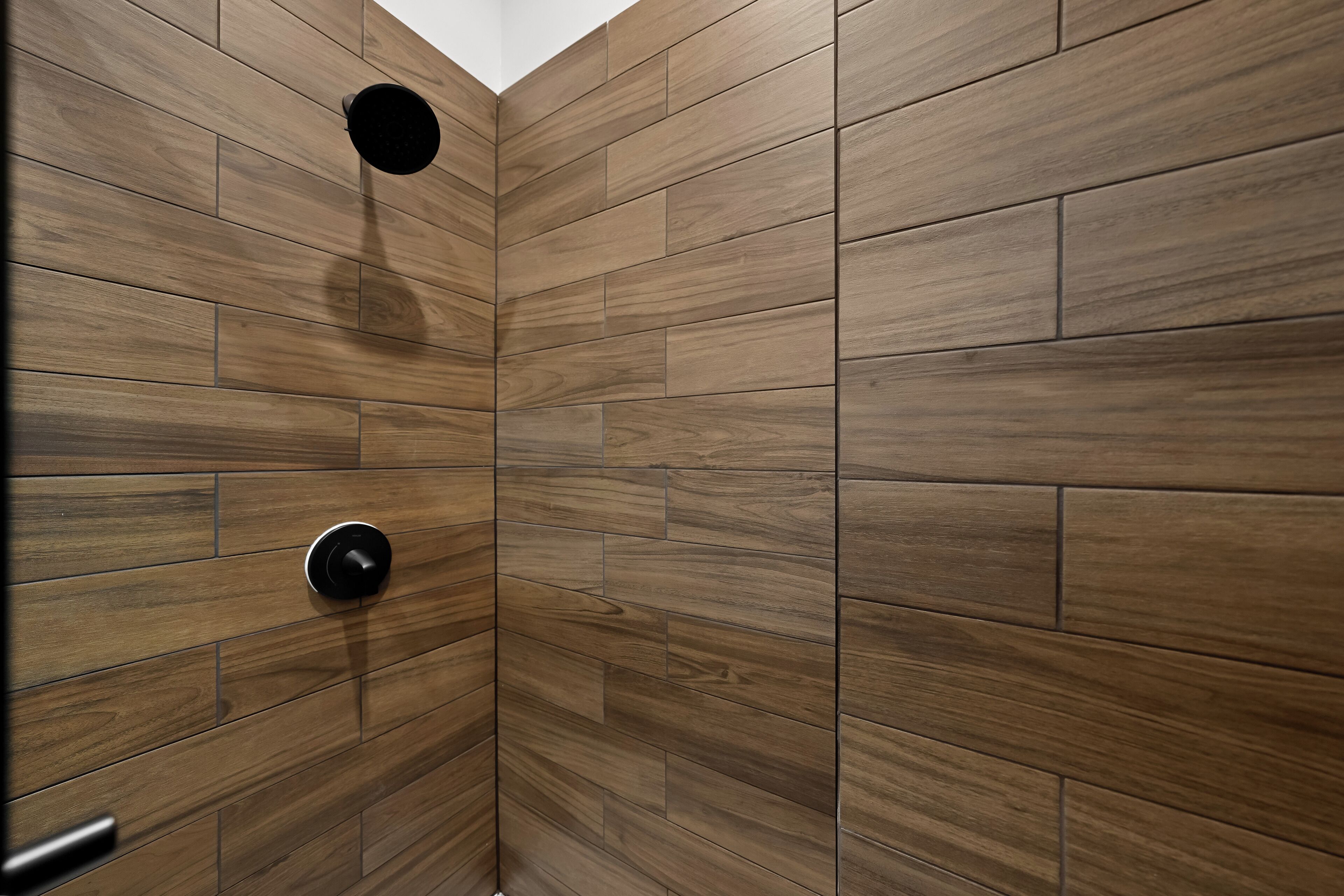 A shower with wooden paneling and a modern faucet.