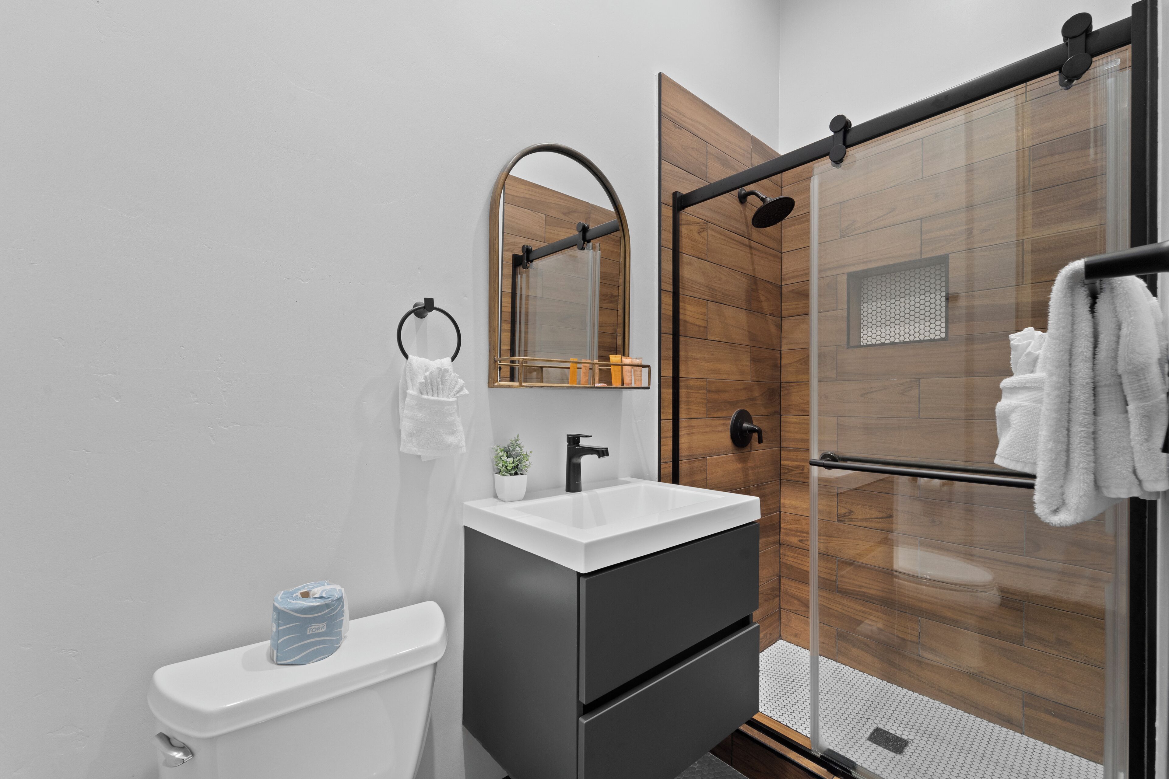 A modern bathroom with a toilet, sink, and shower.